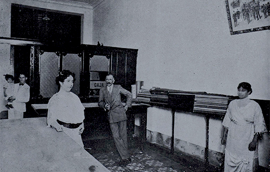 Vista interior de la sastrería de E. S. Resin donde aparece el artista con las directoras de la sección de modas (Ca. 1914).