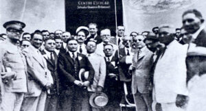 Guáimaro. Momentos de izar la bandera nacional en la antigua casa en donde se reunió la Primera Asamblea legislativa de Cuba el 10 de abril de 1869 (Fotografía abril 1925).