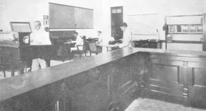 Vista interior de la oficina del contratista Juan Garriga que aparece al centro sentado en su escritorio (Ca. 1919).