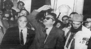 El presidente Manuel Urrutia pronuncia su primer discurso en Palacio desde su despacho oficial. El comandante Rolando Cubela que hixo entrega del Palacio Presidencial escucha atentamente. La Habana, 5 de enero de 1959.