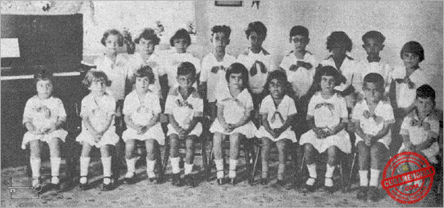 Grupo de niños sentados en el salón de Kindergarten del Colegio Estrella, con un piano al lado, ca. 1928
