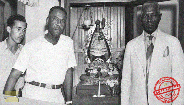 Hombres junto a una imagen de la Virgen de la Caridad del Cobre en una sociedad de franceses en Guantánamo.
