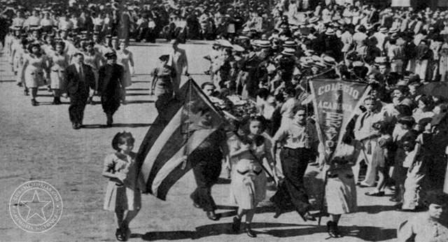 Director y alumnas de la Academia Bravo desfilan con la bandera cubana y el estandarte del colegio durante un homenaje a José Martí en el Parque Central de La Habana, enero de 1939.
